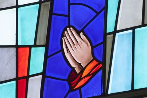 Stained glass window of hands praying. Photo by Jan Snider, United Methodist Communications. 