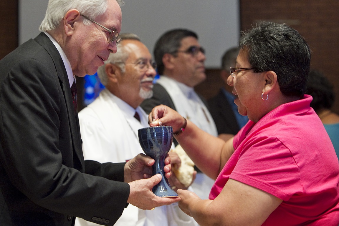 The Rev. Noé Gonzales (left) offers Holy Communion to Nohemi Ramirez during worship  in El Paso, Texas. Photo by Mike DuBose, United Methodist Communications. 